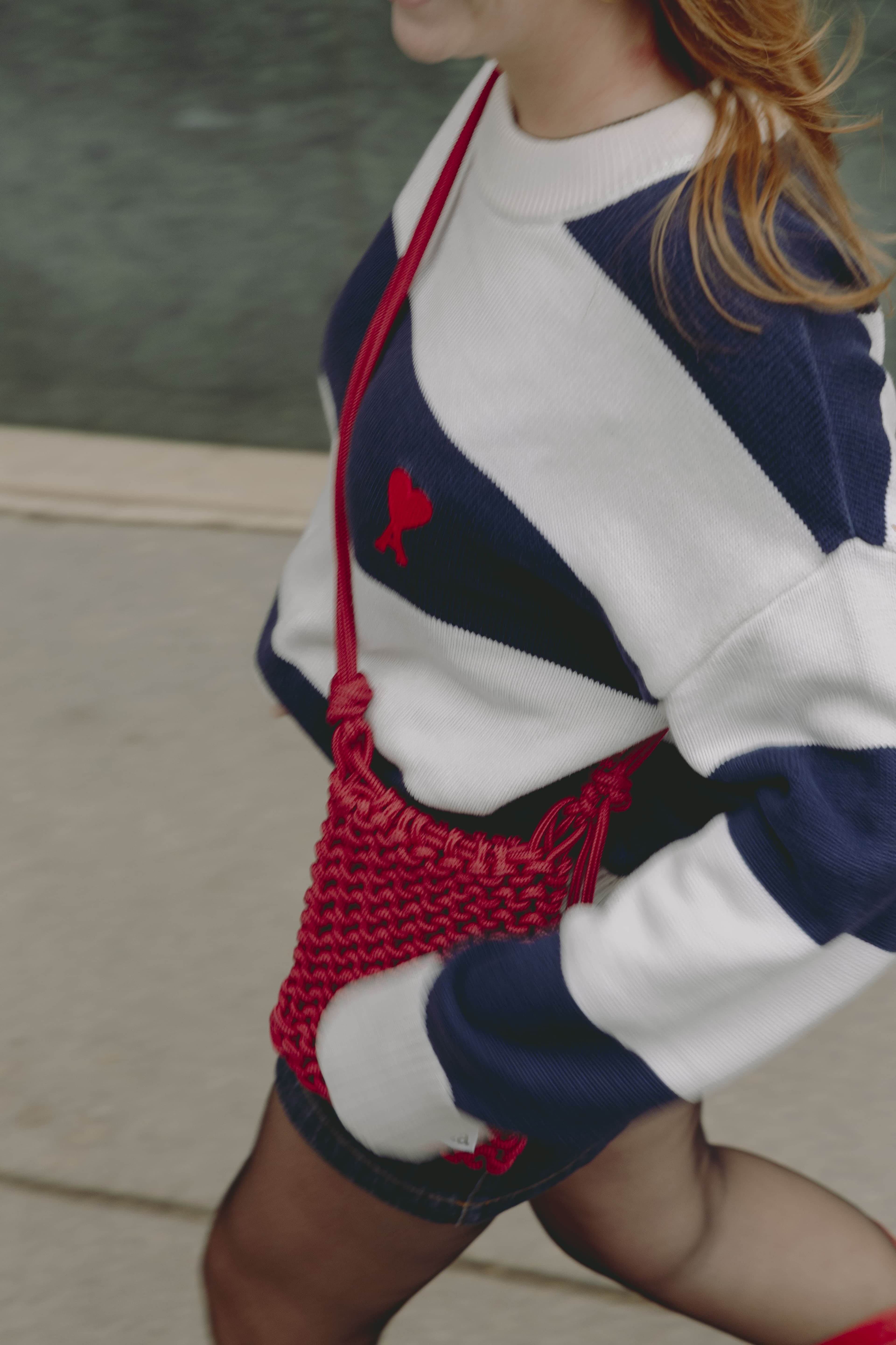 Sac Freïa en paracorde rouge porté en bandoulière sur un pull rayé bleu et blanc