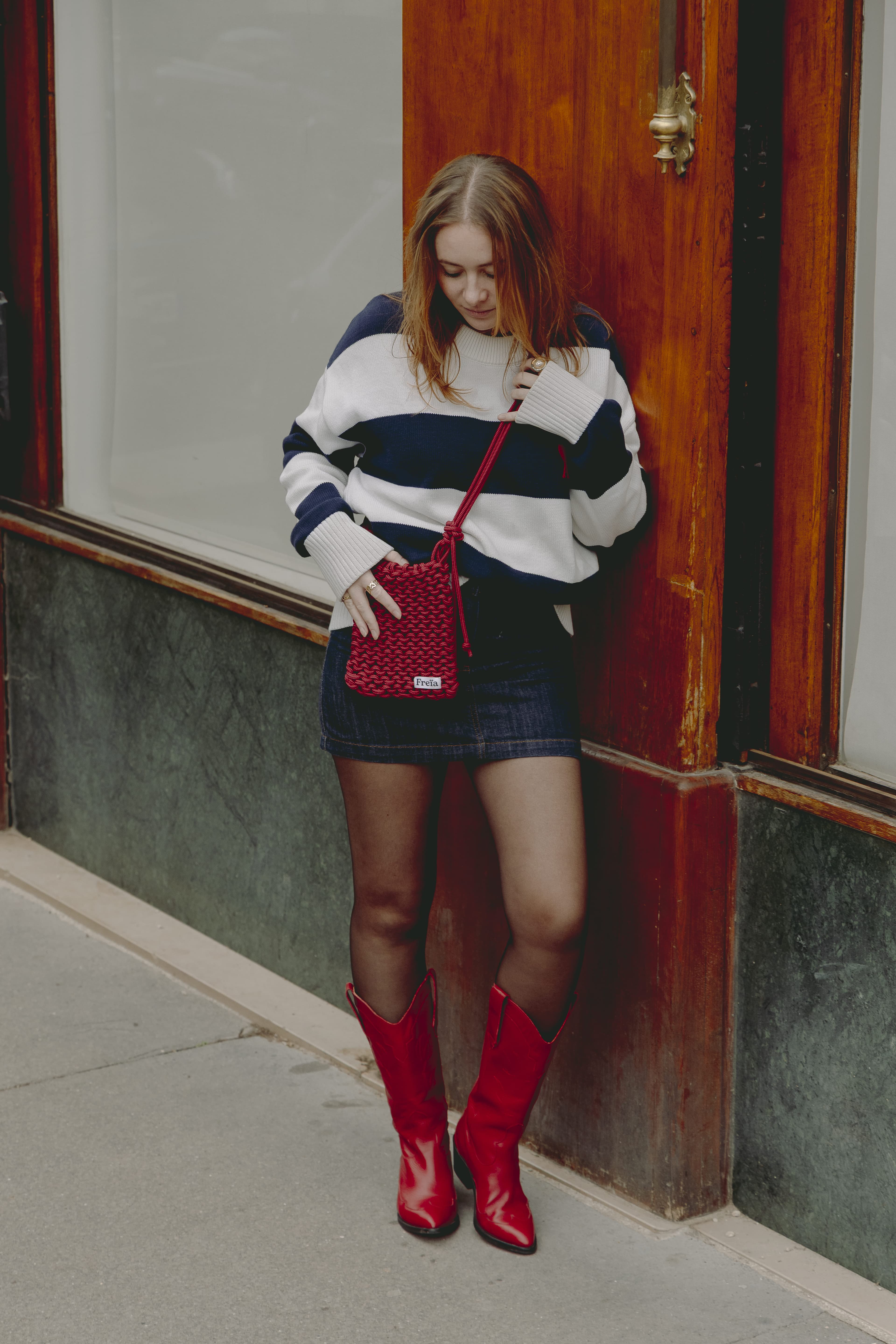 Femme en pull rayé bleu et blanc portant un sac Freïa en paracorde rouge en bandoulière