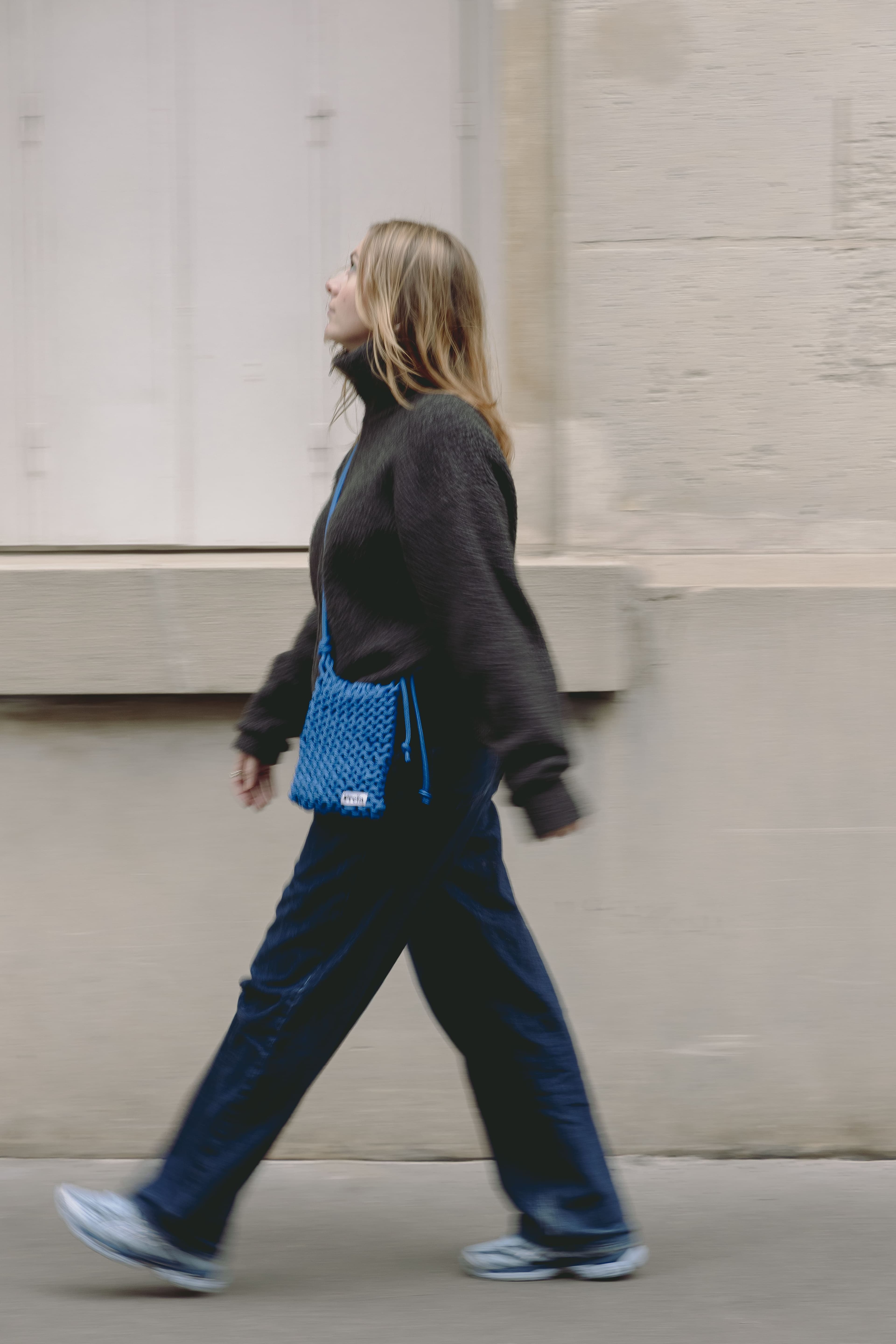 Femme marchant dans une rue parisienne avec un sac Freïa en paracorde bleu en bandoulière